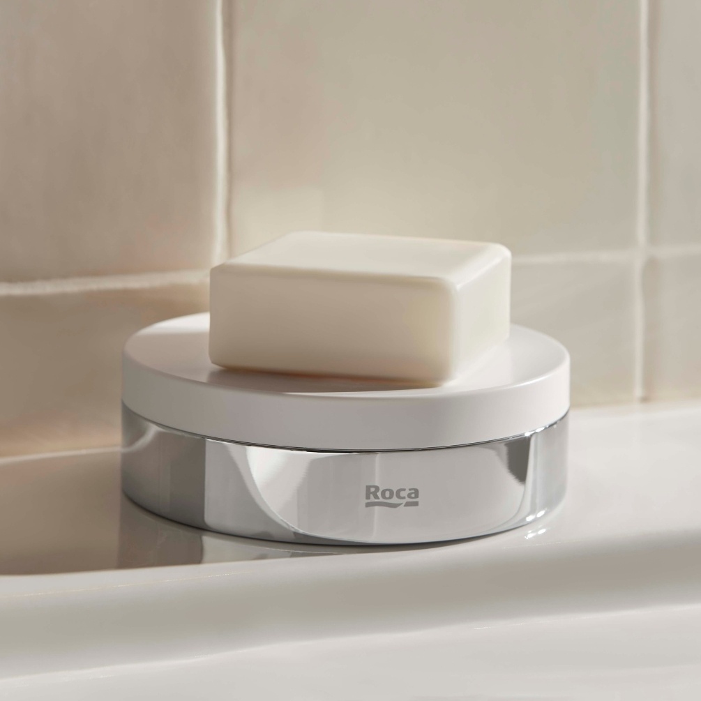 Lifestyle image of the Roca Hotels Chrome Soap Dish on a basin deck, holding a bar of soap